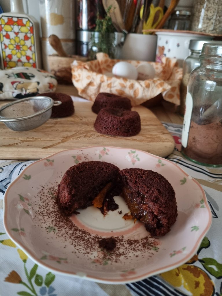 Chocolate fondant broken open, jam running from its centre onto the plate