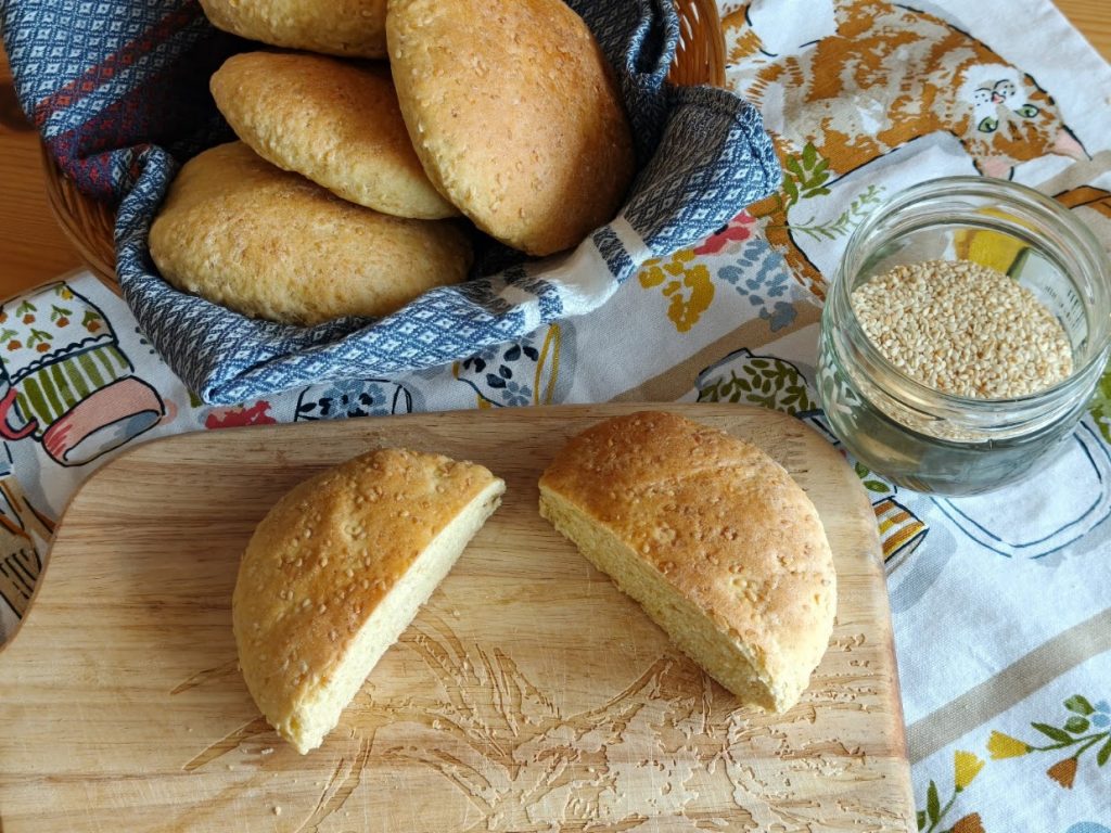 Semolina roll split into two halves on a board, more rolls in a basket behind