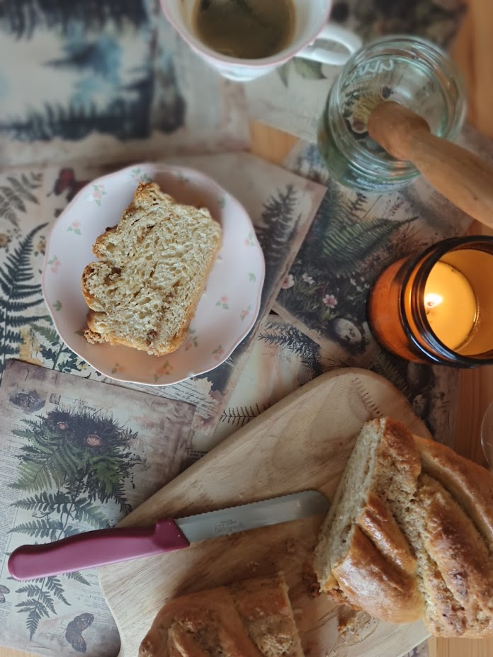 Slices of brioche on a floral plate, with the cut loaf and a bread knife on a wooden board